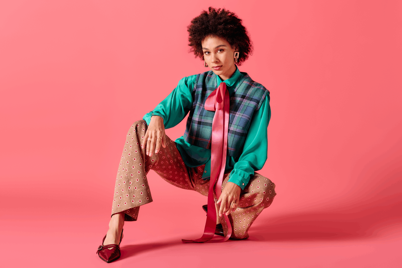 woman-in-plaid-vest-poses-on-pink-backdrop-2026-03-25-07-42-31-utc